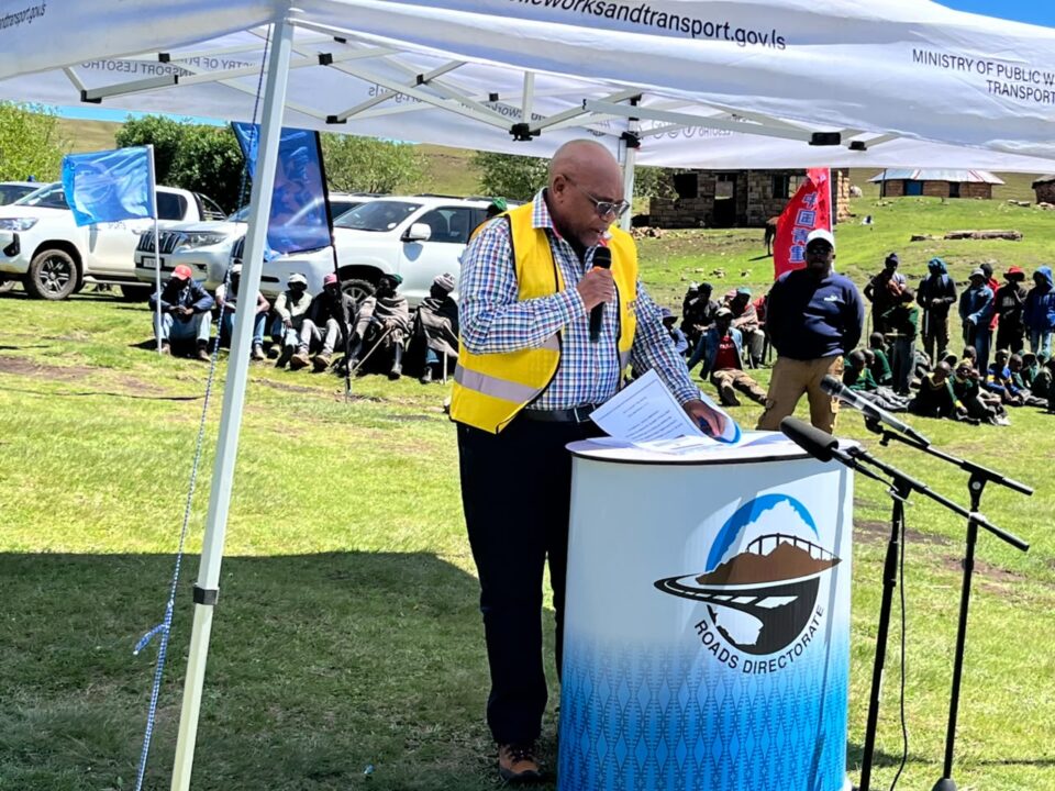 Roads Directorate official speaking at a community project event beneath a Ministry of Public Works and Transport canopy.